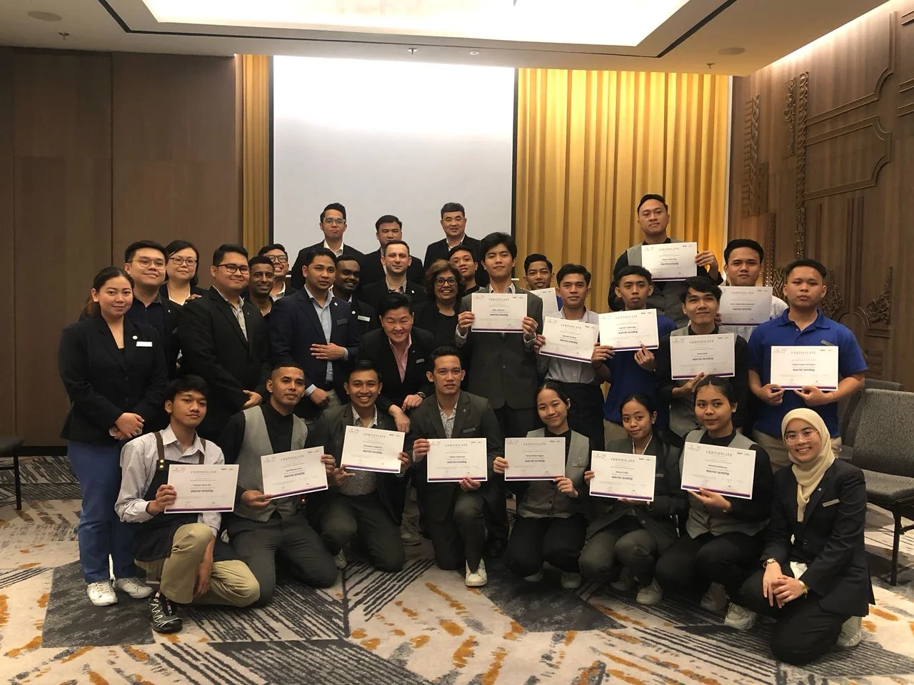 Students and staff gathered with certificates at a graduation celebration